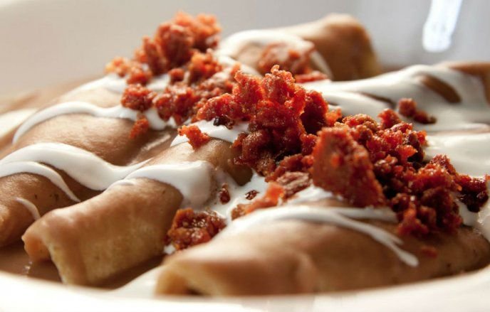 Enchiladas Don Pepe cubiertas con chorizo desmenuzado y crema